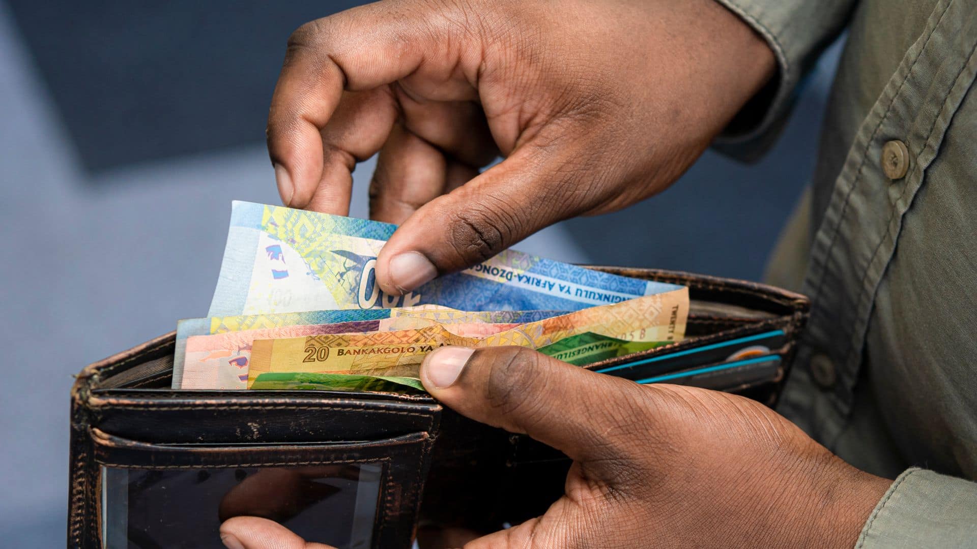 Somebody counting South African banknotes out of a wallet